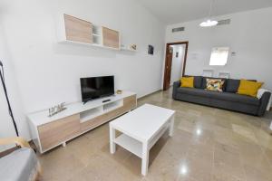 un soggiorno con un divano e una TV di Apartamentos Económicos | 10 minutos Sevilla | BA ad Alcalá del Río