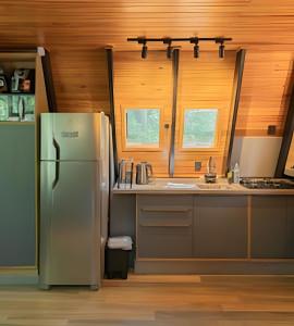 a kitchen with a stainless steel refrigerator and wooden walls at Rosa Cabana de Canela in Canela +10 photos
