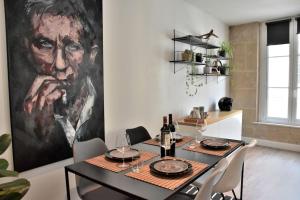 a dining room with a large painting of a man at Hyper Centre - Élégant Appartement au Pied des Restaurants et Boutiques in Caen
