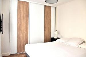 a bedroom with a white bed and sliding glass doors at Hyper Centre - Élégant Appartement au Pied des Restaurants et Boutiques in Caen