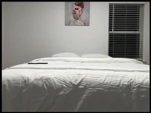 a white bed in a bedroom with a picture on the wall at Banty Villa - Guest Room A in Austin