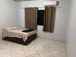 a bedroom with a bed and a window with curtains at Casa 1 andar confortável in Dourados