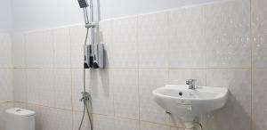 a white tiled bathroom with a sink and a shower at Putri Nyale Bungalows & Rooms in Kuta Lombok +84 photos