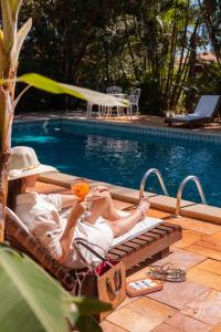 uma mulher deitada numa cadeira ao lado de uma piscina em Pousada Rancho do Ralf em Pirenópolis