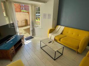 a living room with a yellow couch and a table at Queen Anne Court with FREE PARKING By Prescott Apartments in Abingdon