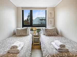 two beds in a room with a window at Depto nuevo 5 estrellas, ubicación insuperable in Puerto Varas