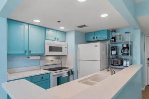 a kitchen with blue cabinets and a white refrigerator at Ocean Front Beach Condo in Panama City Beach