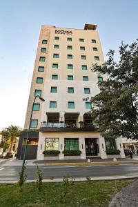 a tall white building with green windows on a street at Moka Boutique Hotel in Torreón