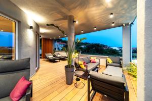 a living room with couches and chairs on a balcony at Rab Rental Villa in Rab