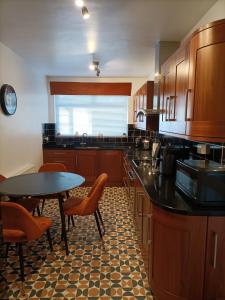 une cuisine avec des armoires en bois et une table et des chaises dans l'établissement Mill cottage, à Carrickfergus