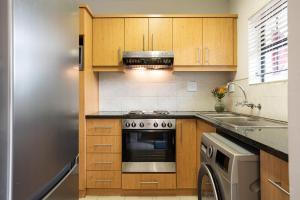 a kitchen with wooden cabinets and a stove top oven at Vino Self Catering Apartment in Stellenbosch