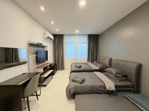 a room with two beds and a desk and a television at Kuching Cozy Comfort 03 - Riverine Diamond Kuching 5 Pax in Kuching