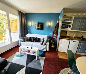 ein Wohnzimmer mit einer weißen Couch und einer Küche in der Unterkunft Résidence Les Terrasses d'Azur - maeva Home - Appartement 2 pièces 4 personnes Sélection MAE-6904 in Isola 2000