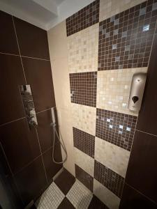 ein Bad mit einer Dusche mit schwarzen und braunen Fliesen in der Unterkunft RMG Home in Fisciano