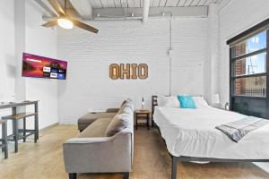 a bedroom with a bed and a couch and a tv at 107-Cozy Loft Haven Parking Fast Wi-Fi Cafe in Cleveland