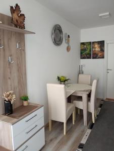 Vrnjačka BanjaにあるApartmani Nanaのテーブルと白い椅子のあるダイニングルーム