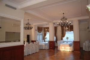 Habitación grande con sillas blancas y lámpara de araña. en Adria, en Bieruń Nowy