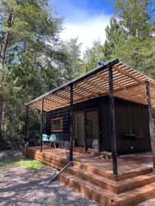 a cabin with a wooden deck in the woods at Cabaña Ensenada, Puerto Varas - 1 ambiente in Puerto Varas