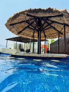 una gran piscina con una sombrilla grande en 3 Atardeceres, Pet Friendly Vista al Mar en Brisas, en Acapulco