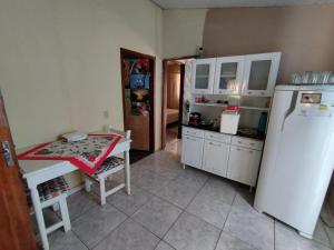 a kitchen with a white refrigerator and a table in it at Casa Pedacinho do Céu in Estivado