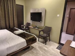 a hotel room with a bed and a desk with a tv at Kedari Residency in Yeraoda