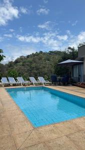 a swimming pool with lounge chairs and a table at Espaço Vida Mury - Casa Mara in Nova Friburgo