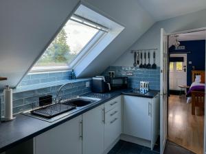 una cocina con fregadero y ventana en The Coach House Knipoch, en Oban