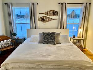 a bedroom with a large white bed with windows at 8 Acres on Betsie River River front Trails Disc golf in Thompsonville