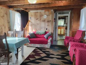 a living room with red couches and a table at Robinson's Cottages in Township of Edmunds