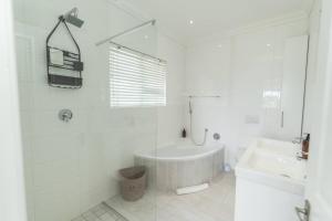een witte badkamer met een bad en een wastafel bij The Nautical Nook in Gqeberha +35 foto's