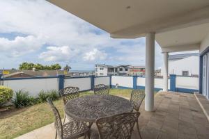 een terras met een tafel en stoelen op een balkon bij The Nautical Nook in Gqeberha