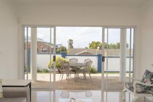een woonkamer met een patio met een tafel en stoelen bij The Nautical Nook in Gqeberha