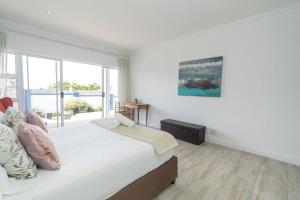 een witte slaapkamer met een bed en een raam bij The Nautical Nook in Gqeberha