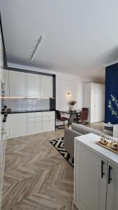 a large kitchen with white cabinets and a living room at Blue Dream Apartment-City Center in Satu Mare