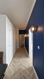 a hallway with white cabinets and a blue wall at Blue Dream Apartment-City Center in Satu Mare +9 photos