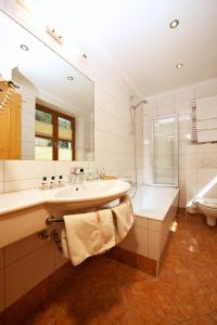 uma casa de banho com um lavatório, uma banheira e um WC. em Hotel Grafenwirt em Wagrain