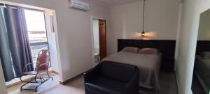 a bedroom with a bed and a chair and a window at Sevili Garden Hotel in Arujá