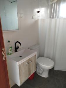 a bathroom with a white toilet and a sink at Aconchego da Montanha in Garopaba