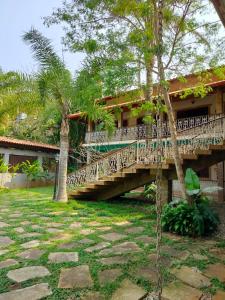 a bridge in front of a house with trees at Mansão Sunset Beach House in São Sebastião