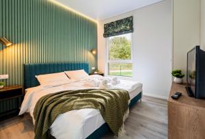 a bedroom with a bed with a green wall at Beržynė Villas in Liepiškės