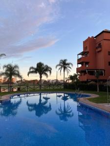 einem großen Pool mit Palmen und einem Gebäude in der Unterkunft Beach Apartment Tropical Golf in Motril