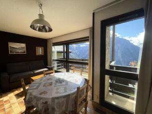 a living room with a table and a large window at Résidence Sequoias - Charmant appartement avec vue époustouflante MAE-5351 in Les Deux Alpes