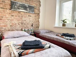 two beds in a room with a brick wall at Apartament Kopalniok in Zabrze