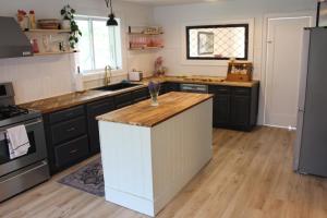 eine Küche mit schwarzen Schränken und einer weißen Insel in der Unterkunft Boutique Accommodation in PEC - Suite 4 in Belleville + 20 Fotos