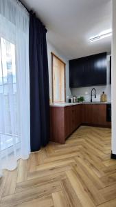a large room with a kitchen with a wooden floor at Apartament Park Chorzów, FV, bezpłatny parking, klimatyzacja in Chorzów