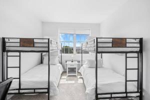 two bunk beds in a room with a window at Family Friendly Deluxe 2 Bedroom Condo Only 25 mins to Soho in Jersey City