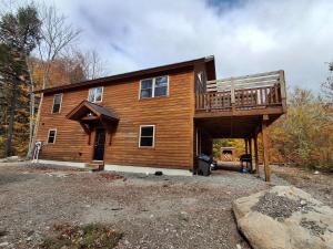 a large wooden house with a large deck at Scoot Cabin - Dogs Welcome! in Carrabassett