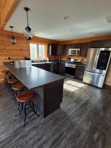 a large kitchen with a large island with bar stools at Scoot Cabin - Dogs Welcome! in Carrabassett