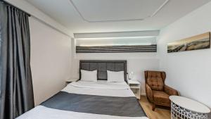 a small bedroom with a bed and a chair at DiDo Diamond Hotel in Dietzenbach