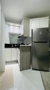 a kitchen with a stainless steel refrigerator and white cabinets at Flat pé na areia no Recreio in Rio de Janeiro